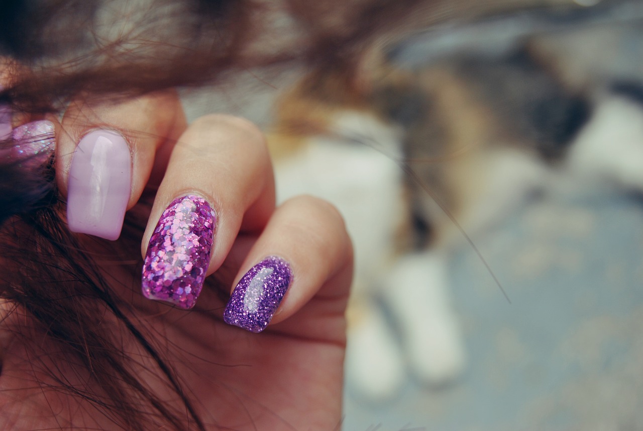 A hand with lilac and purple glitter nails